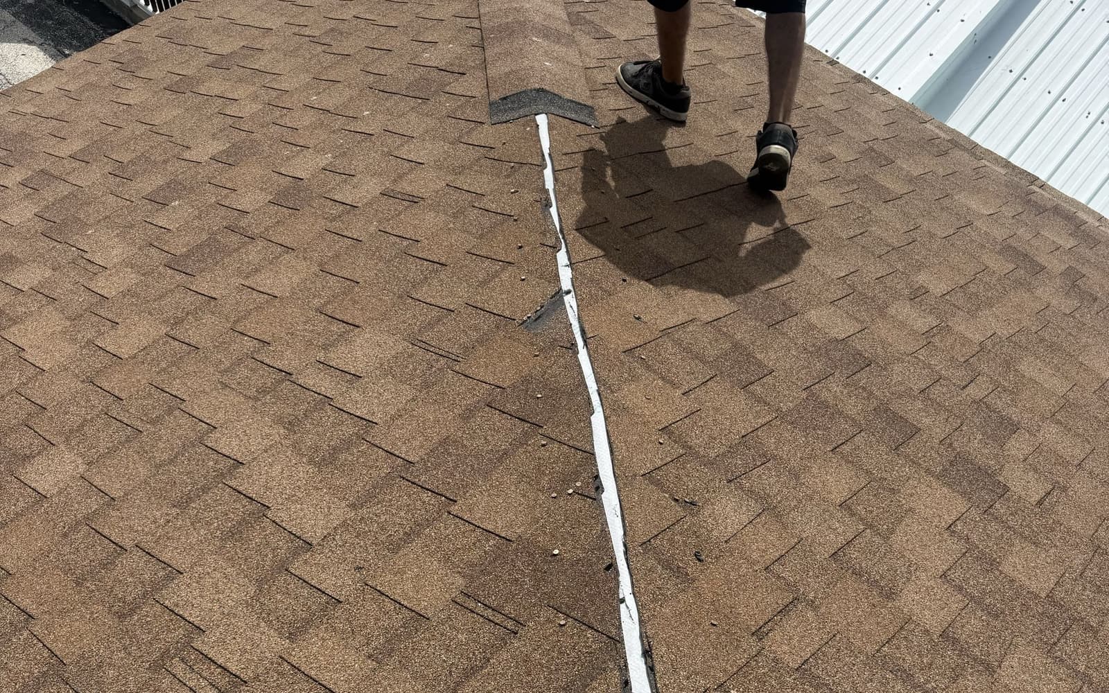 First Coast Roofing crew member on a storm-damaged roof stripped to the decking, with tarps laid out below